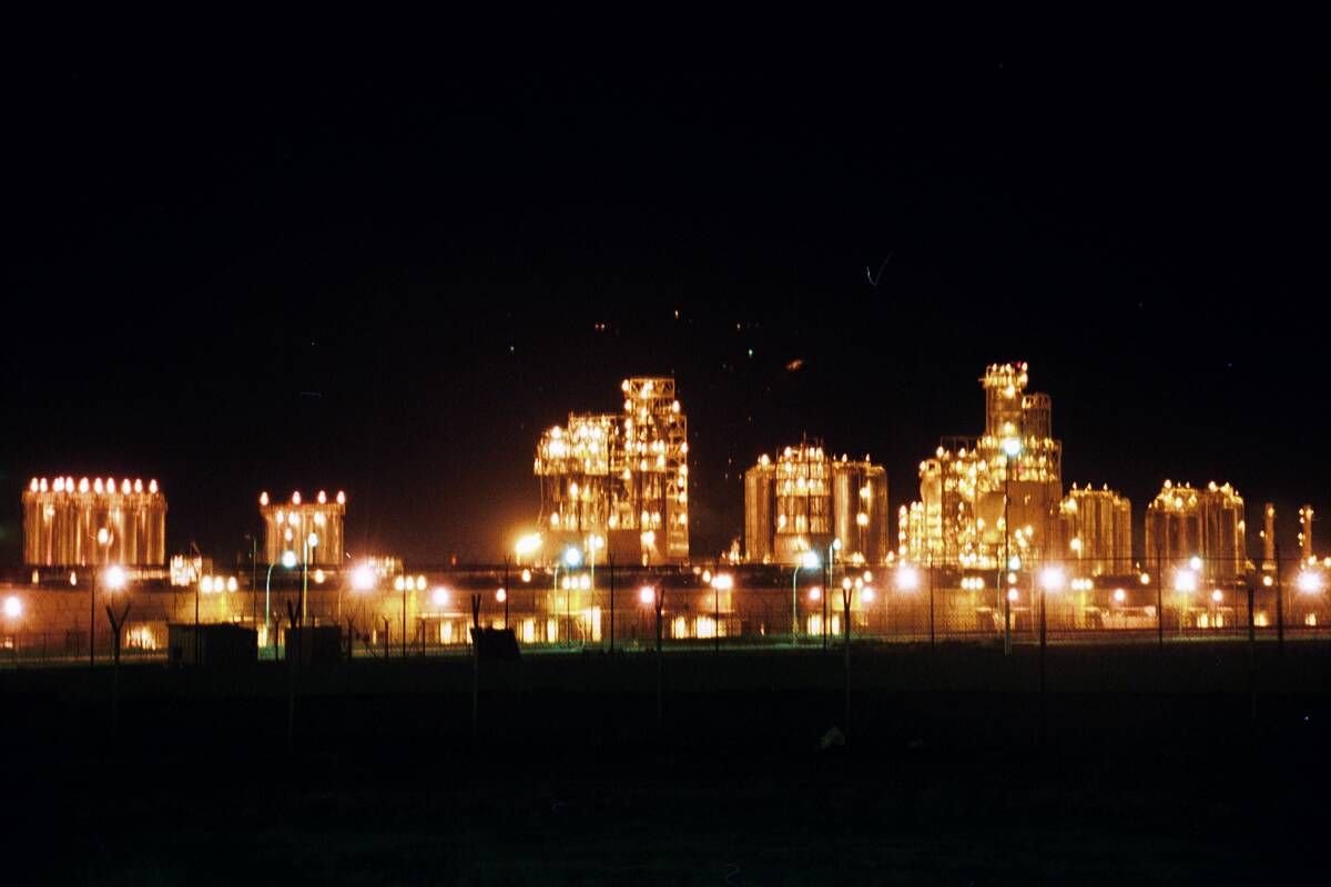 Petrochemische installatie bij nacht met verlichte kolommen en pijpleidingen